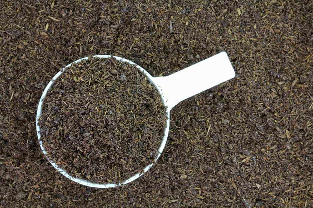Worm castings in a cup on top of more worm castings