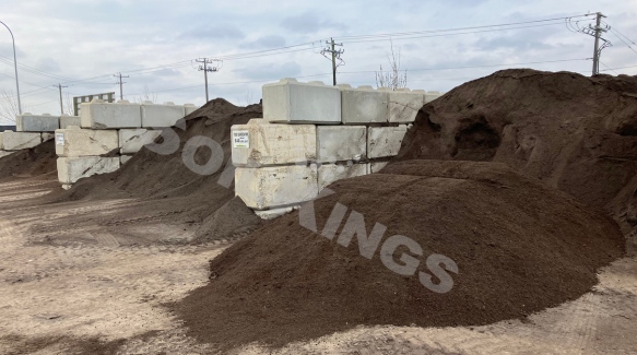 Dark topsoil piles stored at bulk landscaping supply yard for residential and commercial use.