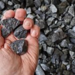 A hand holding a rundle rock, representing rundle rock vs. rundle fines for the best landscaping projects.