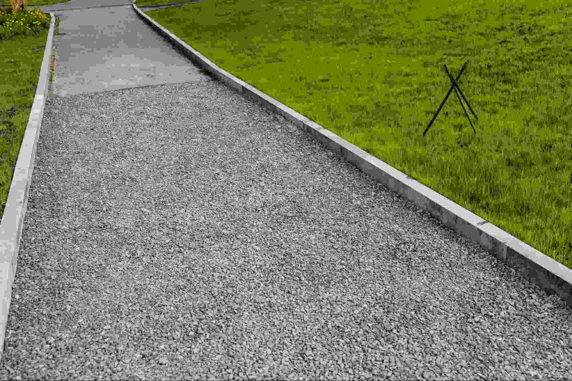 Limestone fines driveway bordered by concrete edging and green lawn, creating a stable, compacted surface that offers durability, drainage, and a clean appearance for residential properties.