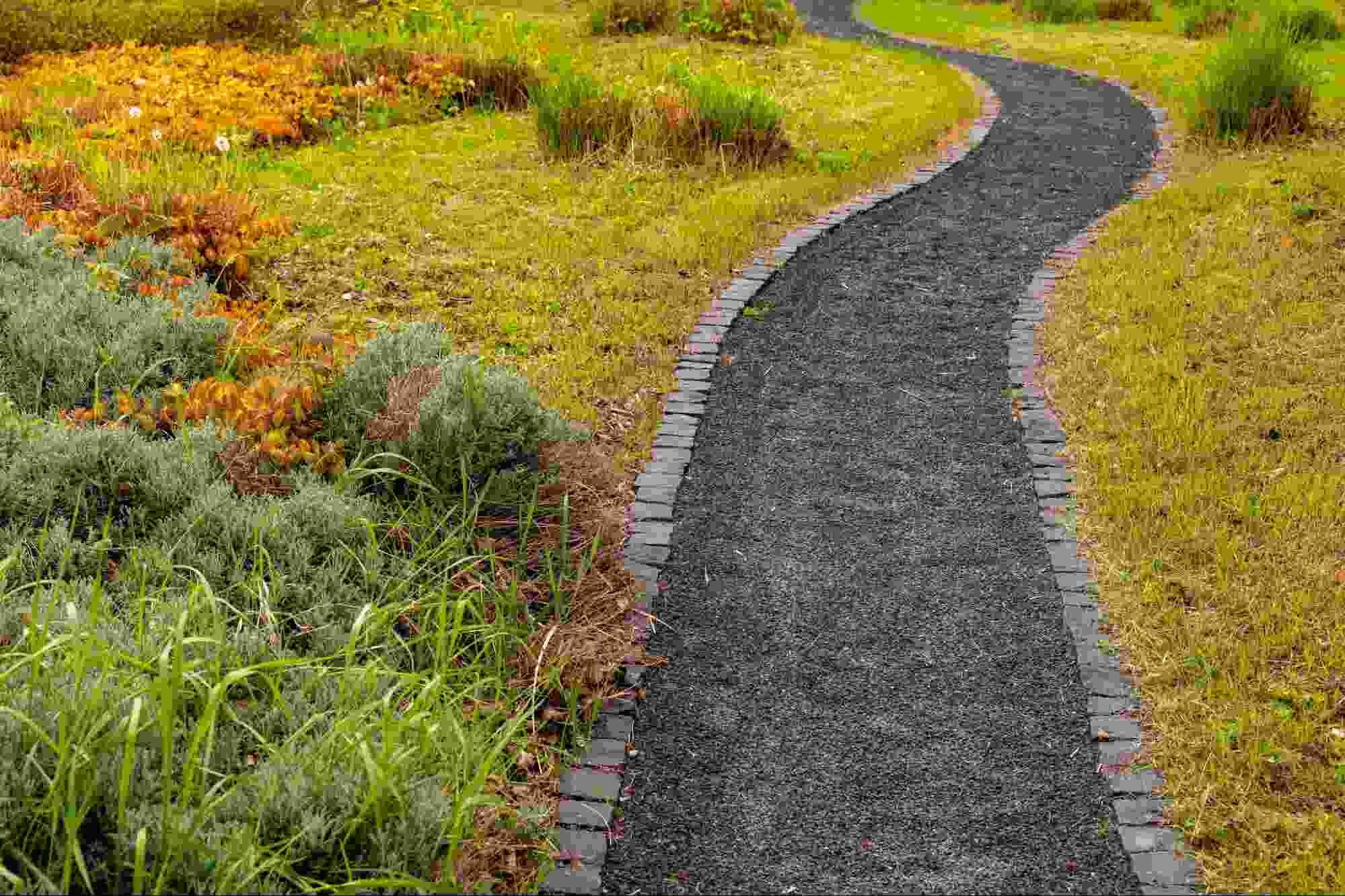 Rundle fines pathway bordered by brick edging and surrounded by natural landscaping, creating a durable, compacted walking surface that blends seamlessly into outdoor garden spaces.