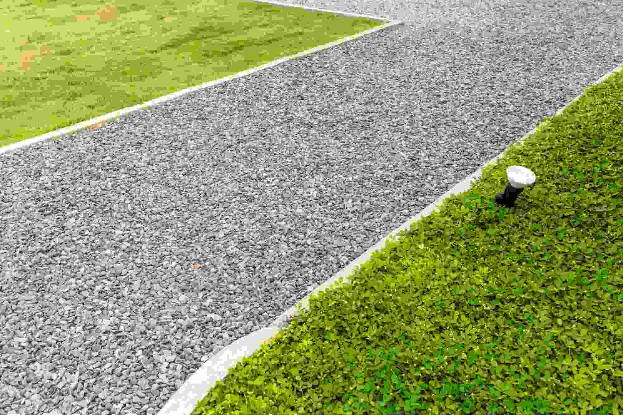 Limestone fines driveway bordered by green grass and landscape edging, providing a compacted, durable surface that enhances drainage and curb appeal for residential properties.